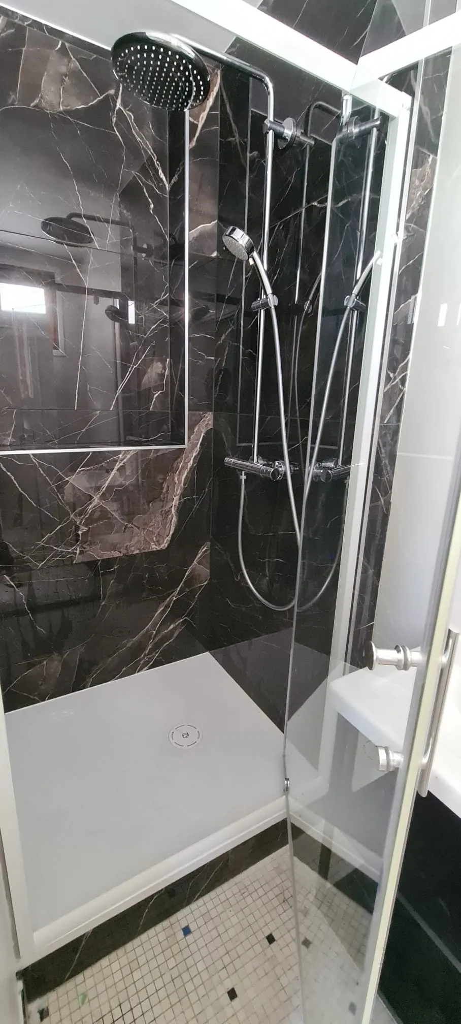 Douche à l’italienne habillée de marbre noir avec parois vitrées et colonne de douche