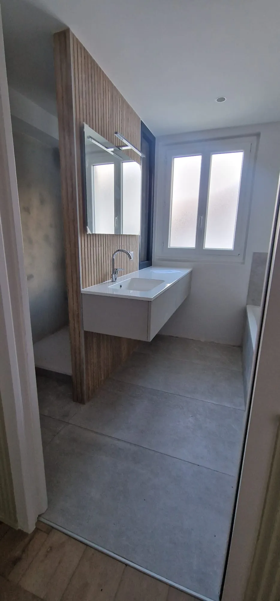 Salle de bain contemporaine avec meuble vasque suspendu blanc, habillage bois et grand miroir
